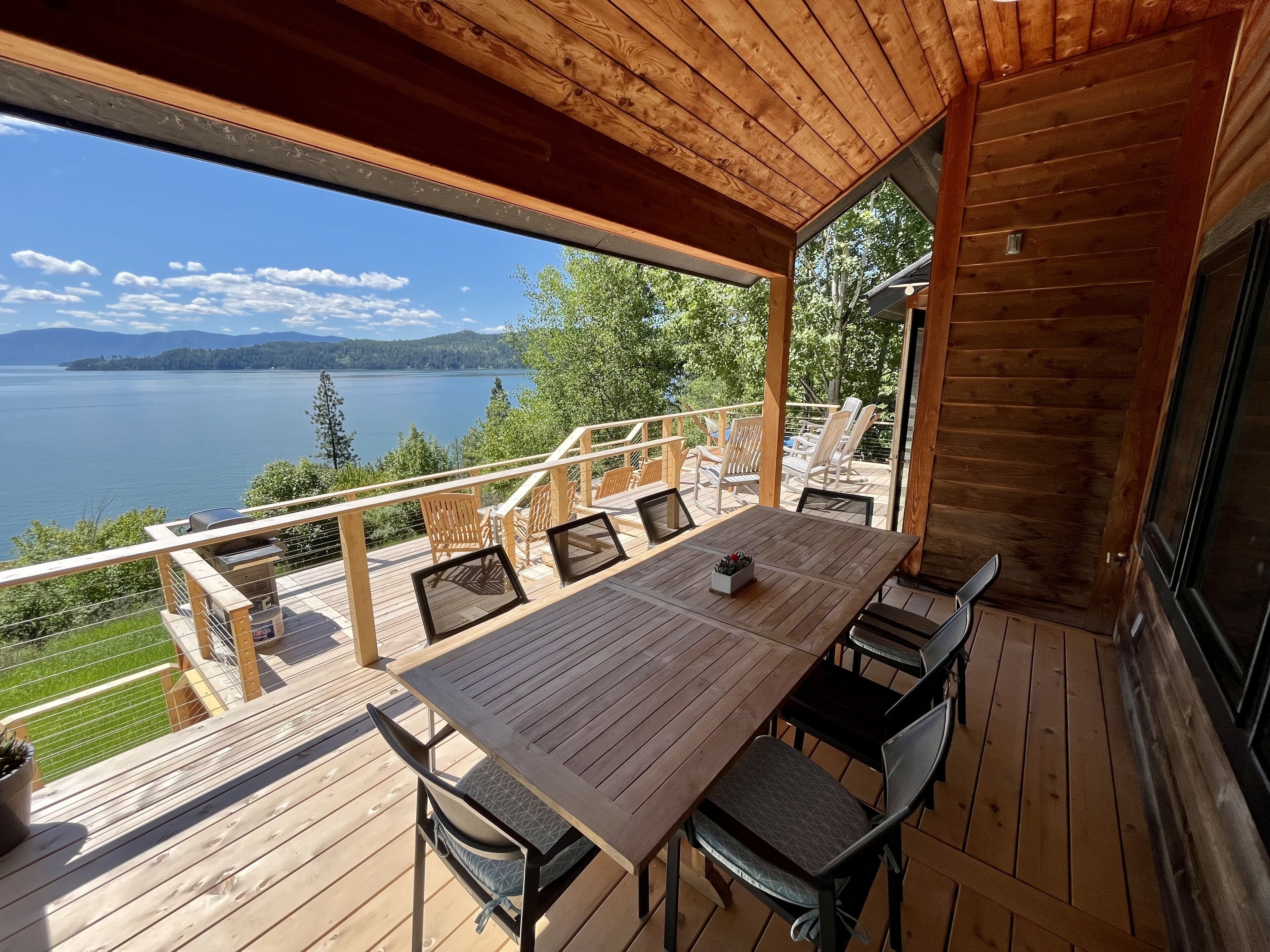 A wooden deck with a table and chairs overlooking a lake.