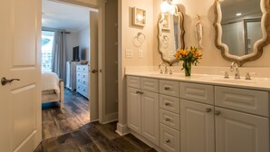 A hotel bathroom with a large mirror, white cabinets, and a vase with flowers. - 🦩Charming Walk-Out Level W/ Upper Pools~No Elevator Needed! Waterscape A233🦩 (Fort Walton Beach)