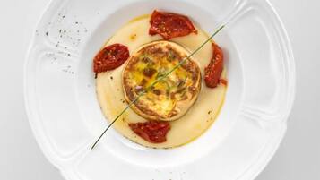 A white plate with a food item, possibly a tart or pie, garnished with red peppers and a green herb.