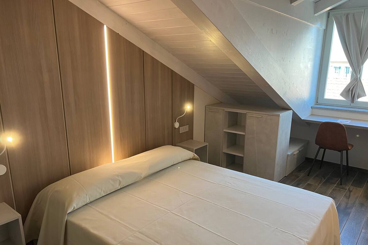 A bedroom with a bed, bedside tables, a desk, and a chair.