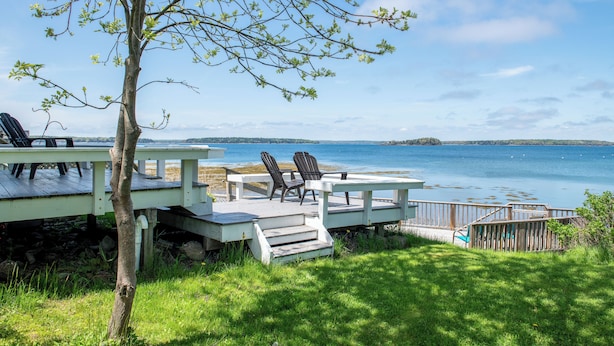 Une terrasse en bois avec des chaises donnant sur un lac.