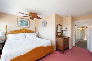 Cozy retreat with a large bed, dresser, and ceiling fan.