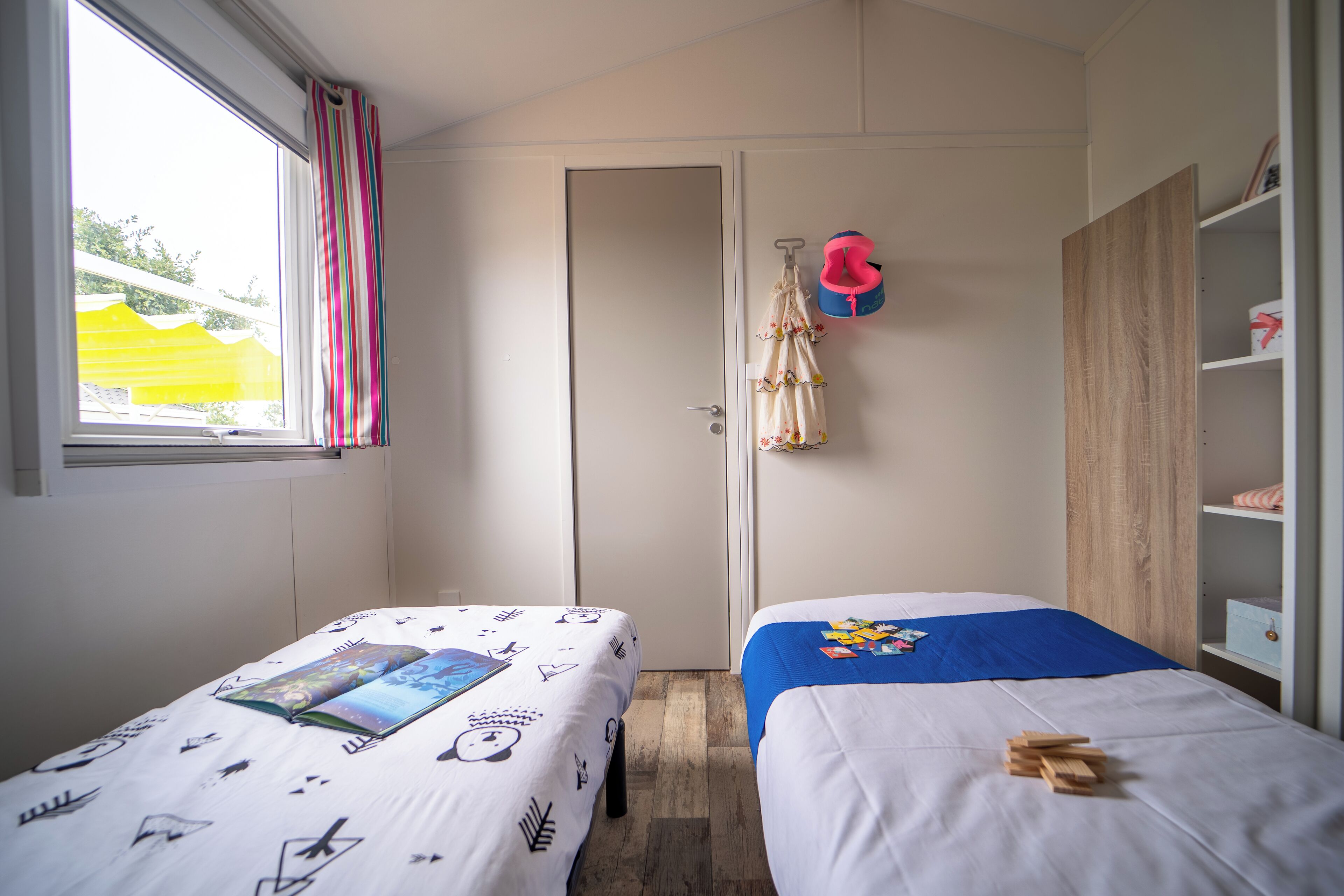 Un dormitorio con dos camas, un armario y una ventana con cortinas.