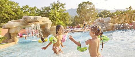 A water park with a pool, water features, and a wooden deck.