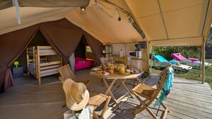 Un hébergement sous tente comprenant un coin repas, un lit superposé et une kitchenette.