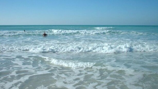 Een strand met golven en een heldere lucht.