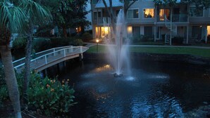 Een hotel met een waterfontein, een brug en een keurig onderhouden tuin.