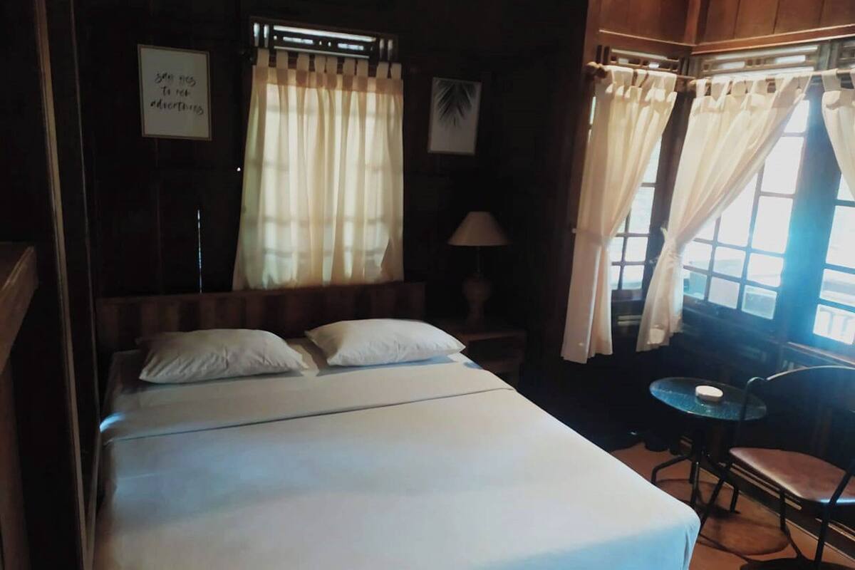 Una habitación de hotel con una cama, una mesita pequeña y cortinas.