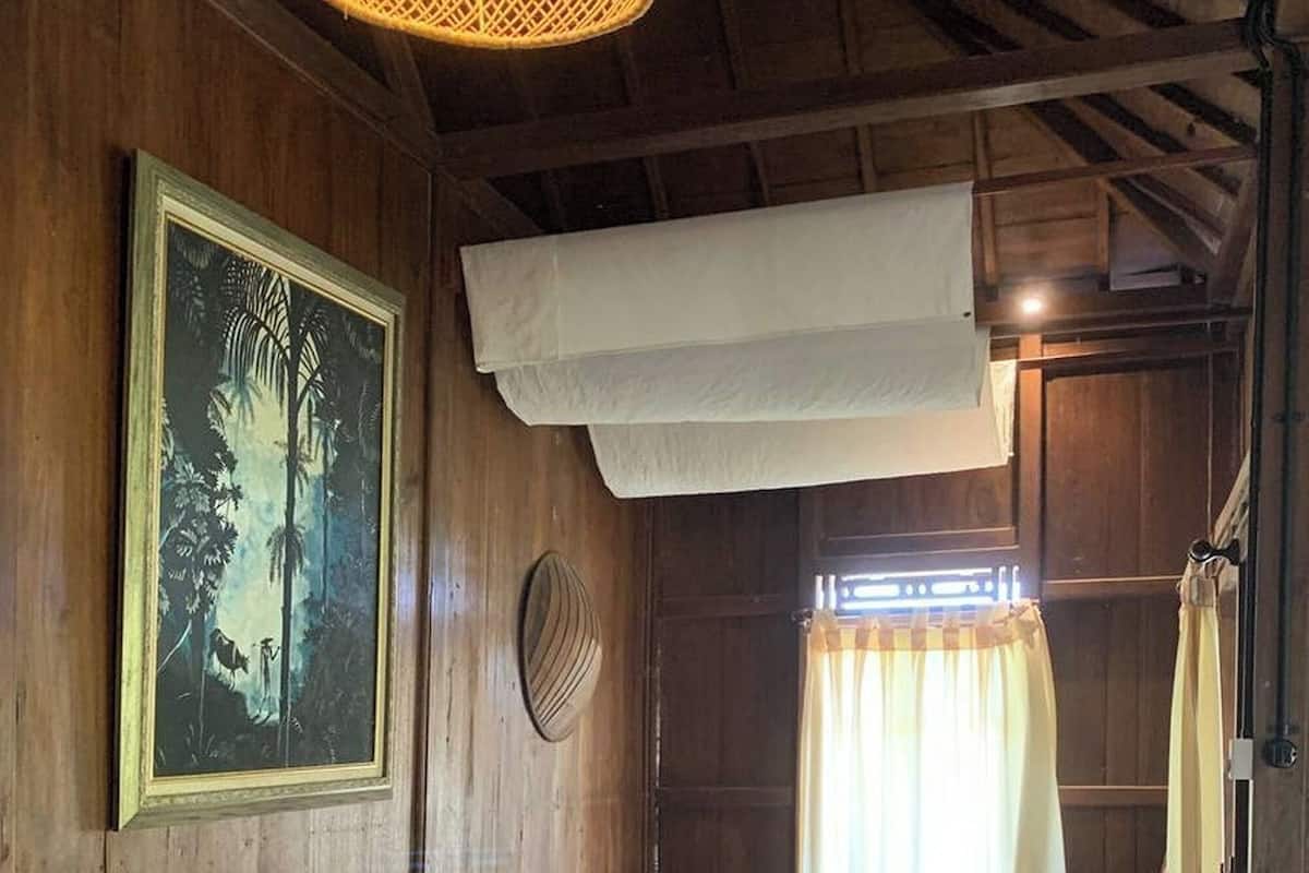 Una habitación de madera con una cama, un televisor, una lámpara de fibra y un cuadro en la pared.