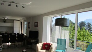 A modern living room with a sofa, armchairs, a coffee table, and a dining area with chairs and a table.