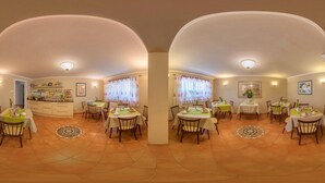 A dining area with multiple tables and chairs, a kitchen in the background, and a tiled floor. - Happy House das fröhliche Urlaubszuhause (Krumpendorf am Woerther See)