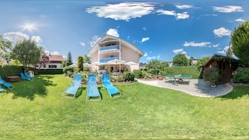 A hotel with a large lawn, multiple lounge chairs, and a building with a balcony.
