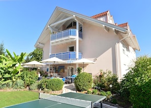 A two-story building with a balcony, outdoor seating, and a ping pong table.