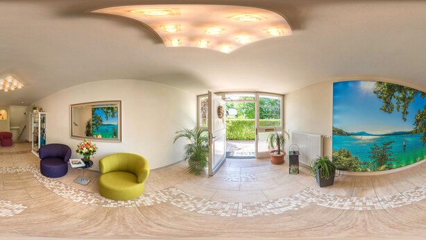 A spacious room with a curved ceiling, a large window with a view of the sea, and a curved wall with a mural of a beach scene. - Happy House das fröhliche Urlaubszuhause (Krumpendorf am Woerther See)