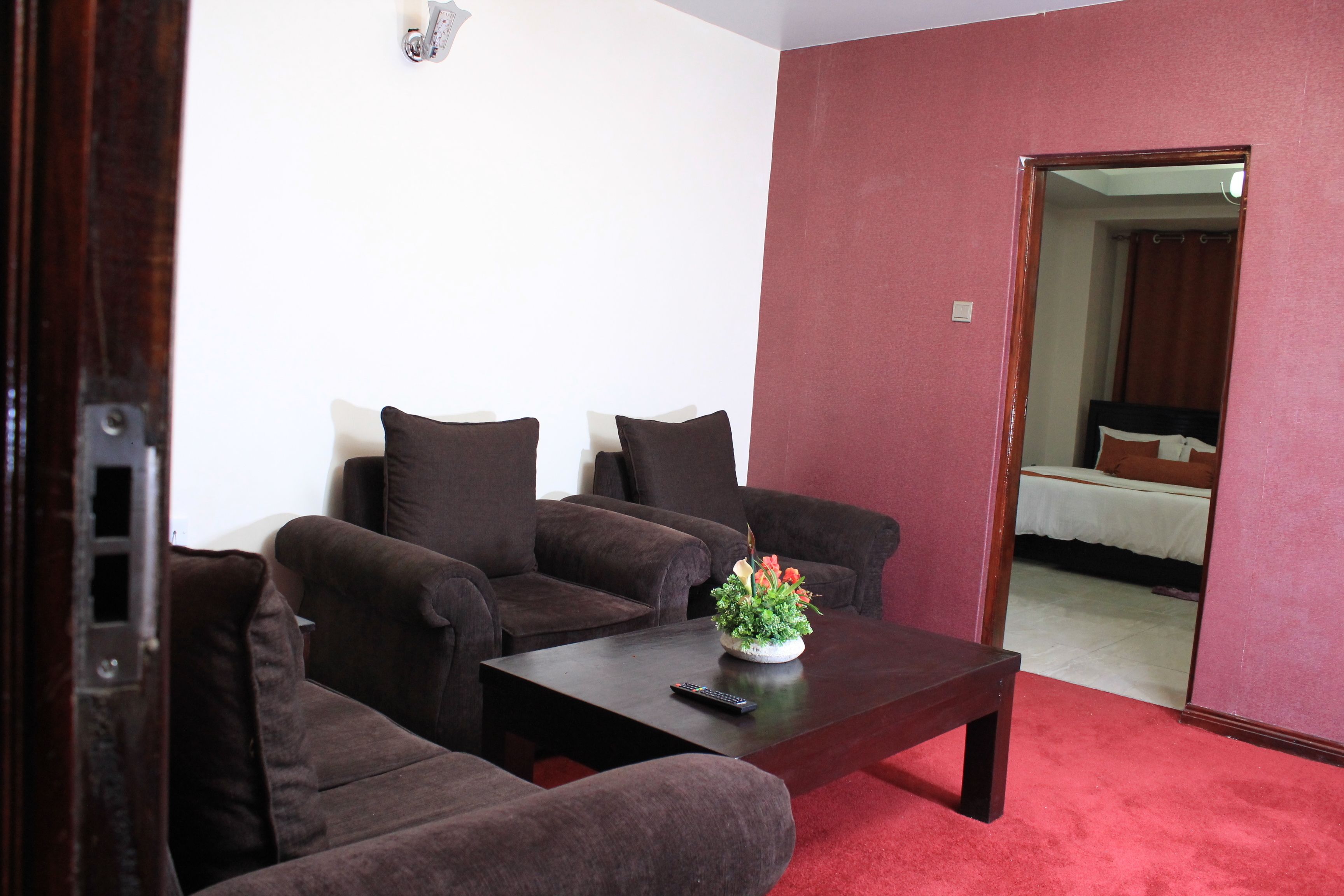 Ein Zimmer mit zwei braunen Sofas, einem kleinen Tisch mit Blumenvase und einem roten Teppich.