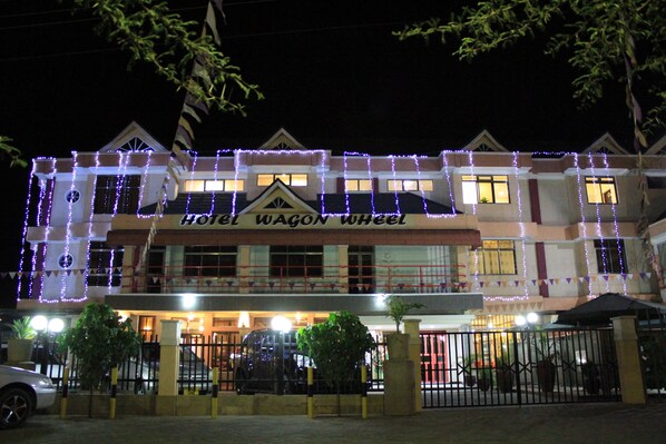 A hotel with a sign reading "Hotel Wagon Wheel." It features a traditional architectural style with a balcony and a gated entrance.