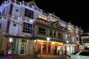 A hotel with a two-story facade, multiple balconies, and a Christmas tree decoration.