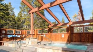 Eine Holzterrasse mit Whirlpool, Steintreppe und Metallgeländer.