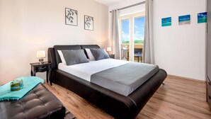 A bedroom with a large bed, a nightstand, a lamp, a window with curtains, and a view of the outdoors. - Villa Coridigo (Tinjan)