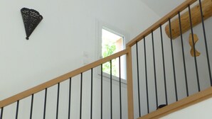 A wooden staircase with black railings, a small window, and a wall-mounted decorative item. - Charming contemporary gîte: wooded property, private pool, Luberon view (Cavaillon)