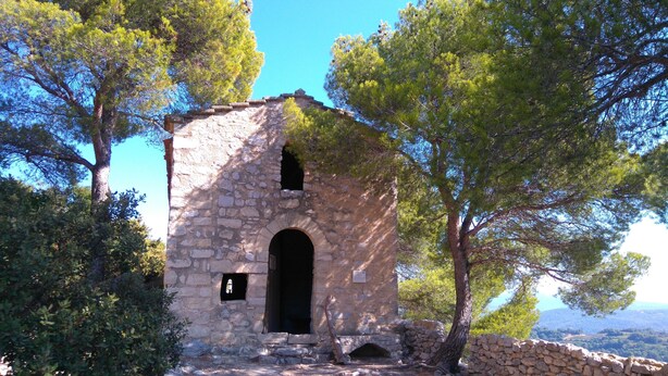 An ancient stone building with a central arched doorway, surrounded by trees and a stone wall. - Charming contemporary gîte: wooded property, private pool, Luberon view (Cavaillon)