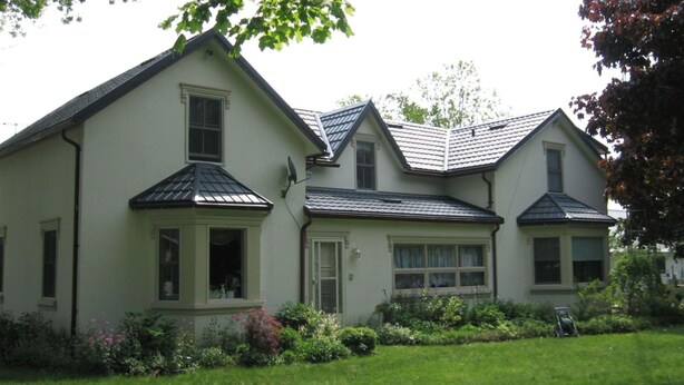 A two-story house with a gabled roof, a front porch, and a well-maintained lawn. - Angel House B&B (Clearview)