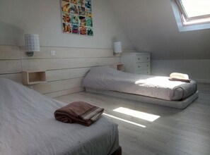 Een slaapkamer met twee bedden, een klein nachtkastje, een wandklok en een prikbord.