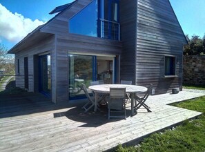 Een modern huis met een groot terras en een eethoek.