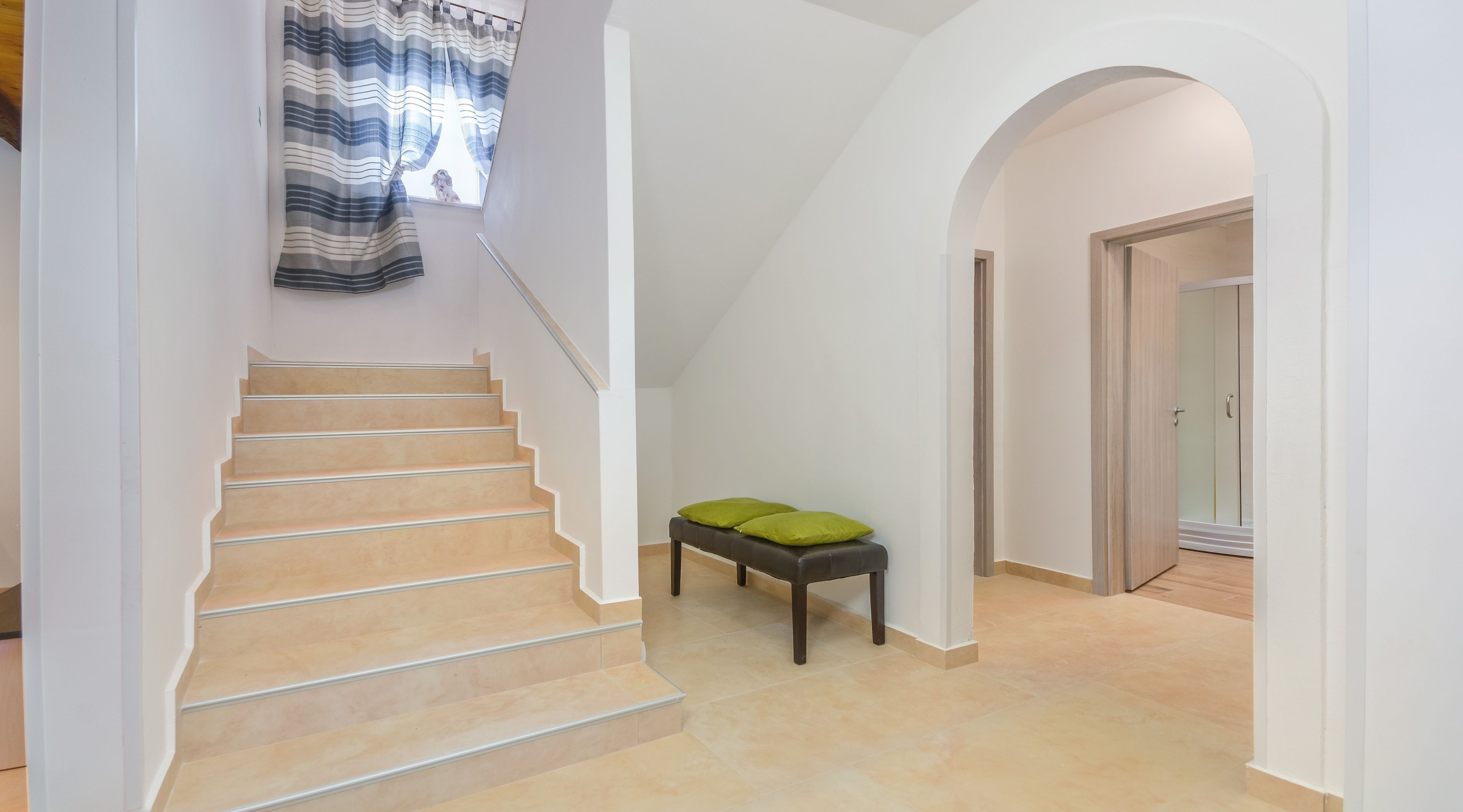 A staircase with beige steps and a dark wooden bench with green cushions.