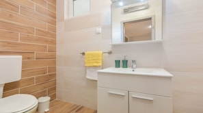 A bathroom with a wooden wall, a white sink, a mirror, and a yellow towel. - Villa Martin (Tinjan)