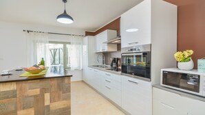 Una cocina moderna con una isla de madera, electrodomésticos de acero inoxidable y vistas al exterior.