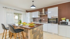 Una cocina moderna con una isla central, taburetes de bar, una cafetera y un microondas.