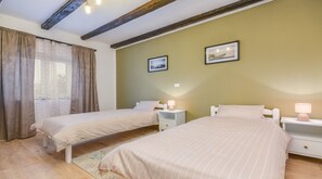 A bedroom with two single beds, a window with curtains, and a wall with two framed pictures. - Villa Martin (Tinjan)