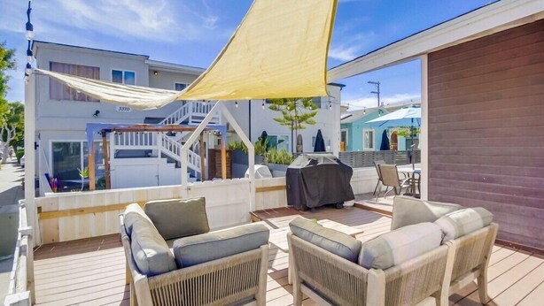 A wooden deck with wicker furniture and a yellow canopy.