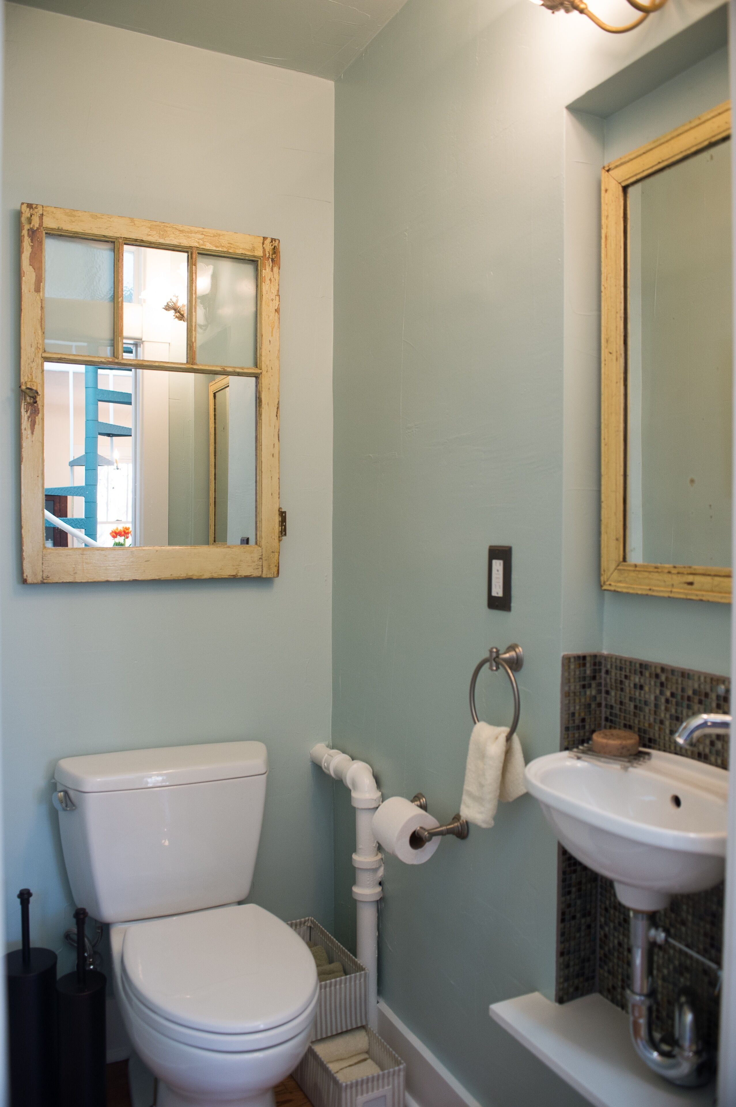A bathroom with a toilet, sink, and mirrors.
