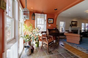 A cozy living room with a fireplace, a piano, and a large window.