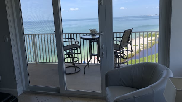 Een balkon met uitzicht op de oceaan, een stoel en een kleine tafel.