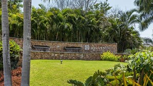 A stone wall with a sign reading "LOS VENEROS" surrounded by lush greenery and palm trees.