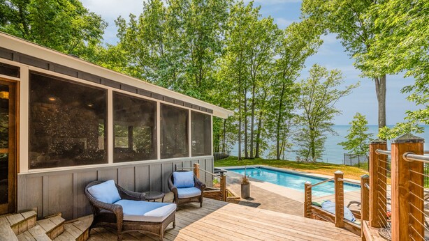 A wooden deck with two wicker chairs and a pool. - Blue Water Retreat - Spacious Lake Michigan retreat with In-ground pool (Benton Harbor)