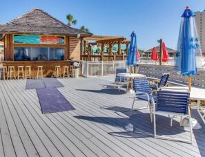 Een houten terras met buitenmeubilair en een bar.