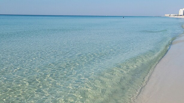 Una playa con aguas poco profundas y cristalinas y una orilla arenosa.