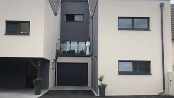 Een modern gebouw met twee verdiepingen, een plat dak, een garage en een klein balkon.