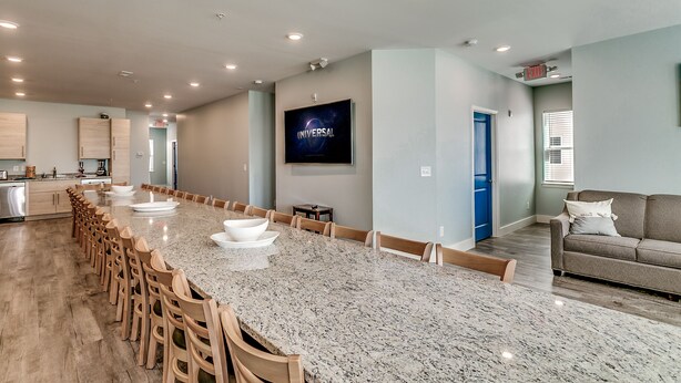 A spacious kitchen with a long granite countertop, wooden chairs, and a built-in oven. - ACROSS FROM the BEACH SLEEPS 50, HUGE POOL+SPA, CHEF'S KITCHEN, GAME+MEDIA ROOM (North Myrtle Beach)