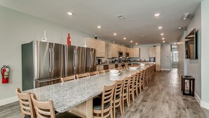 A modern kitchen with a long island, stainless steel appliances, wooden cabinets, and a granite countertop. - ACROSS FROM the BEACH SLEEPS 50, HUGE POOL+SPA, CHEF'S KITCHEN, GAME+MEDIA ROOM (North Myrtle Beach)
