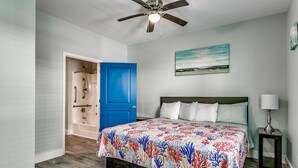 A bedroom with a bed, a ceiling fan, a blue door, and a painting on the wall. - ACROSS FROM the BEACH SLEEPS 50, HUGE POOL+SPA, CHEF'S KITCHEN, GAME+MEDIA ROOM (North Myrtle Beach)