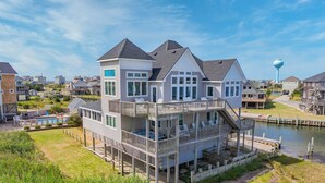 Une maison à plusieurs étages située au bord de l’eau, dotée d’un balcon, d’une piscine et d’un quai.