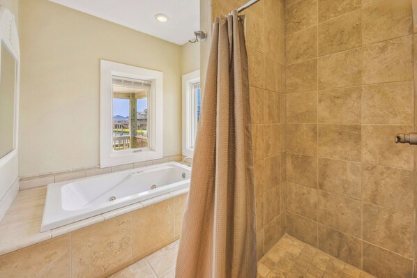 A bathroom with a bathtub, shower curtain, and a window with a view of buildings.