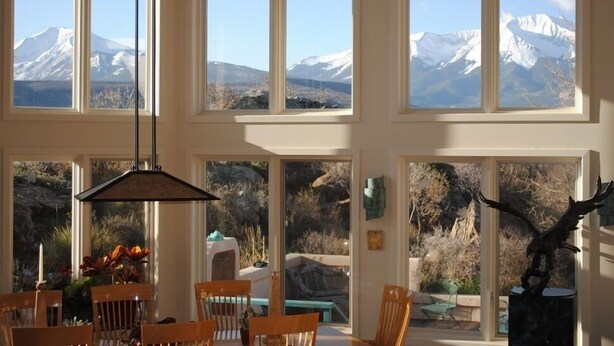 A dining area with a view of snow-capped mountains through large windows.