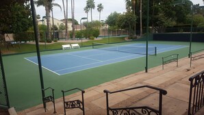 En tennisbana med nät, bänkar och ett staket.