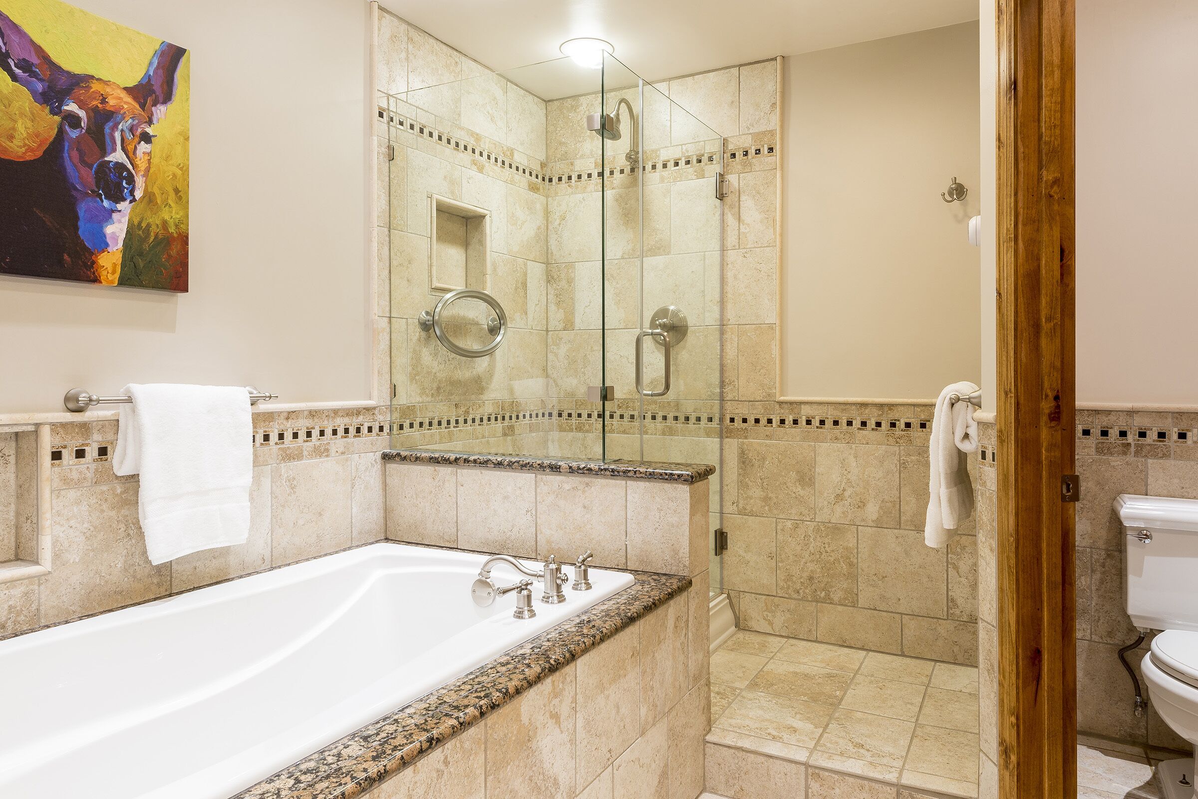 A modern bathroom with a large bathtub, a glass-enclosed shower, and a toilet.